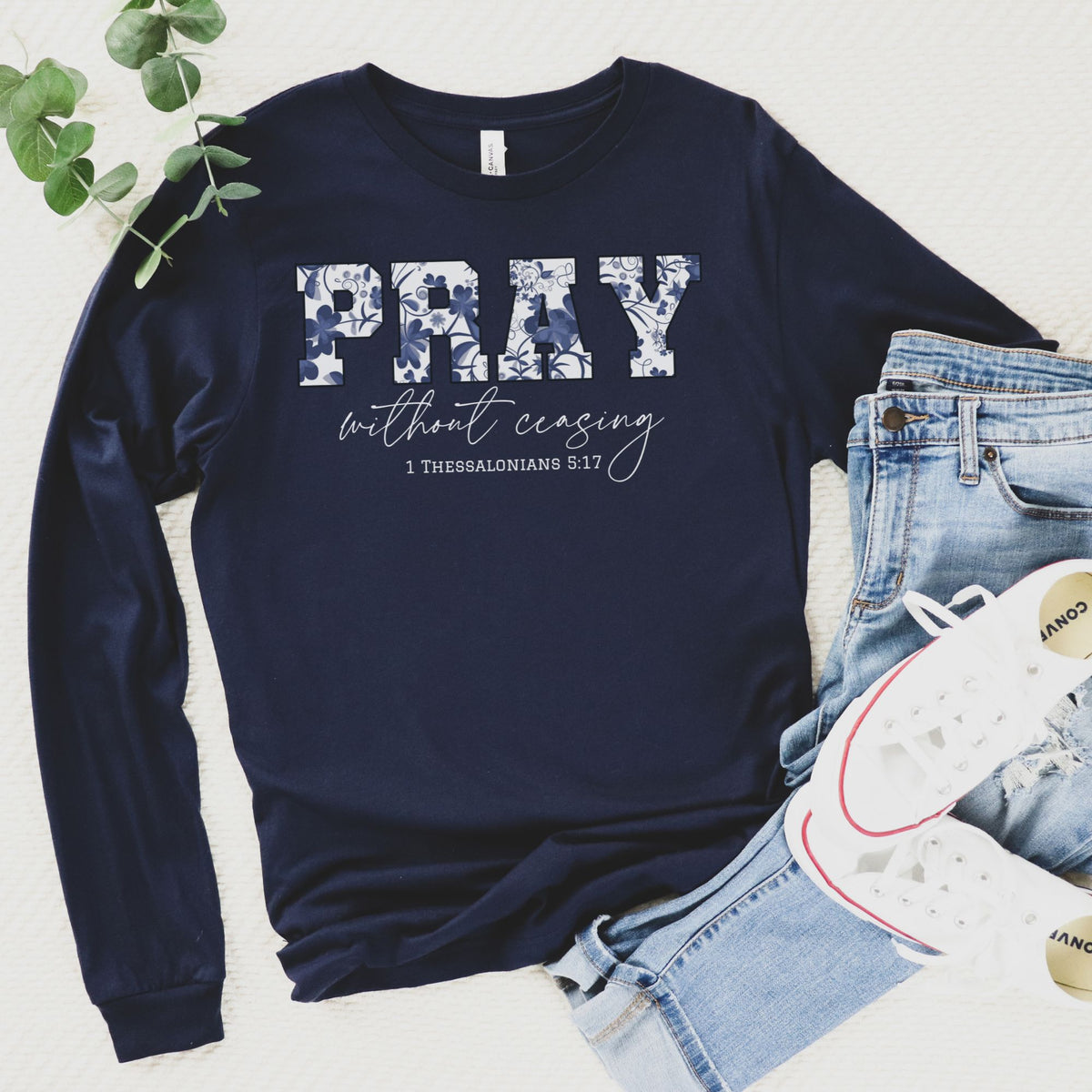 Navy blue sweatshirt with 'PRAY without ceasing' text, paired with jeans and sneakers on a light background.