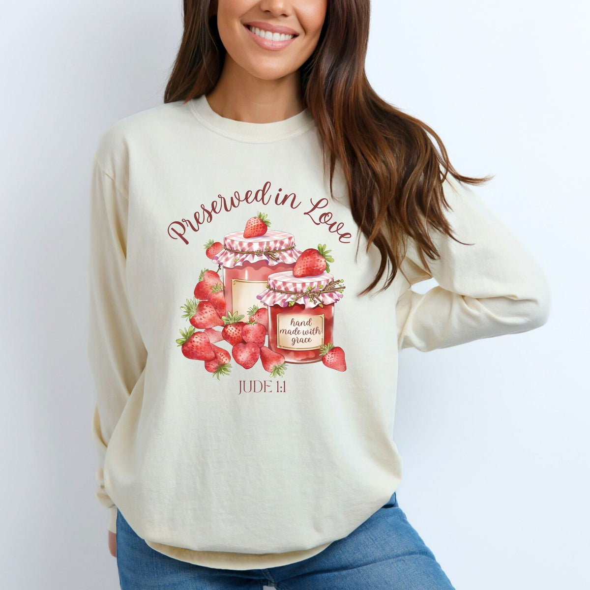 Person wearing a cream sweatshirt with strawberry design and text on a white background