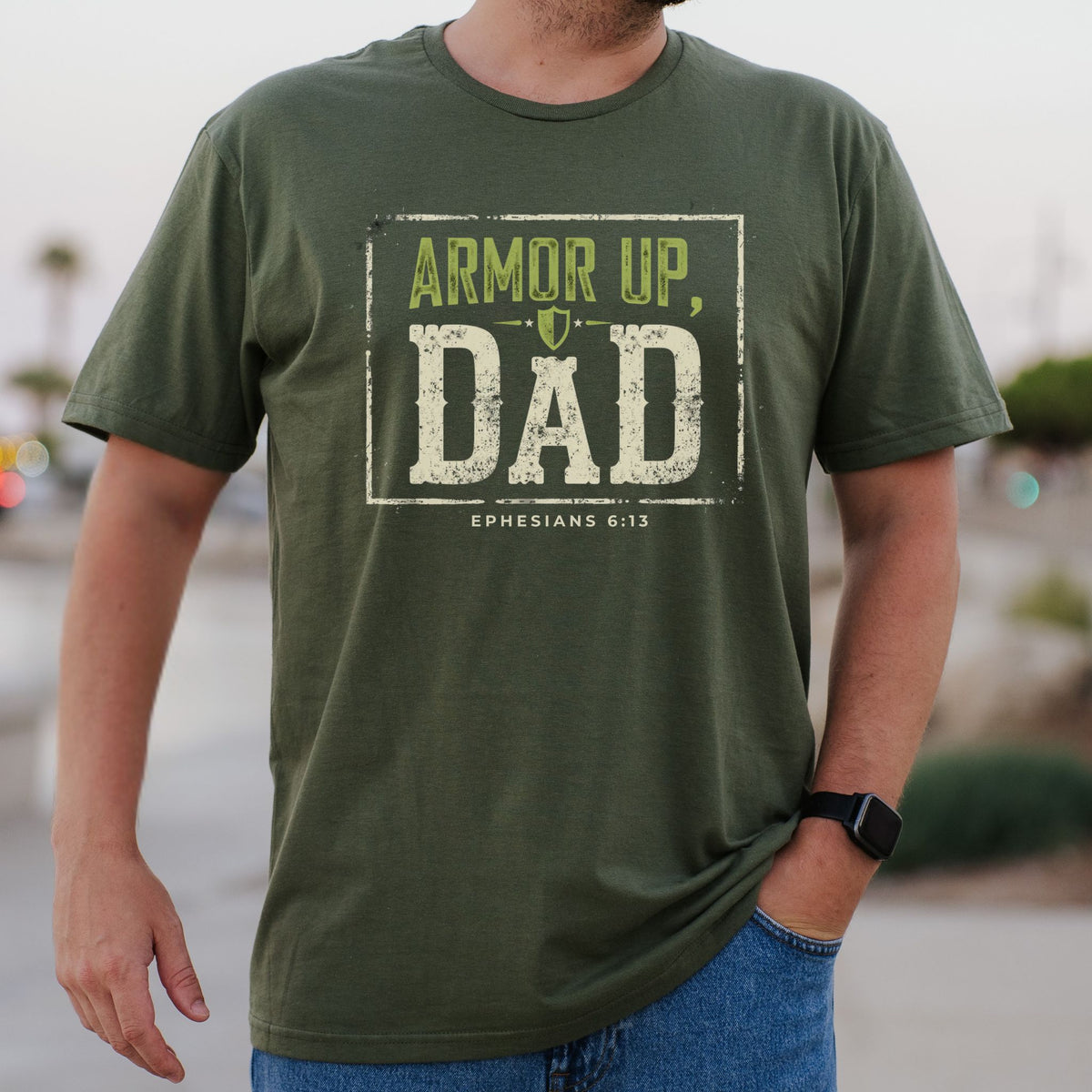 Person wearing a green t-shirt with 'Armor Up, Dad' text