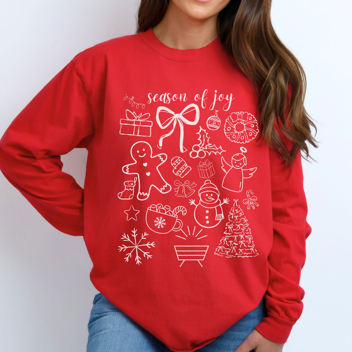Red long sleeve shirt with white Christmas-themed graphics and 'season of joy' text on a plain background