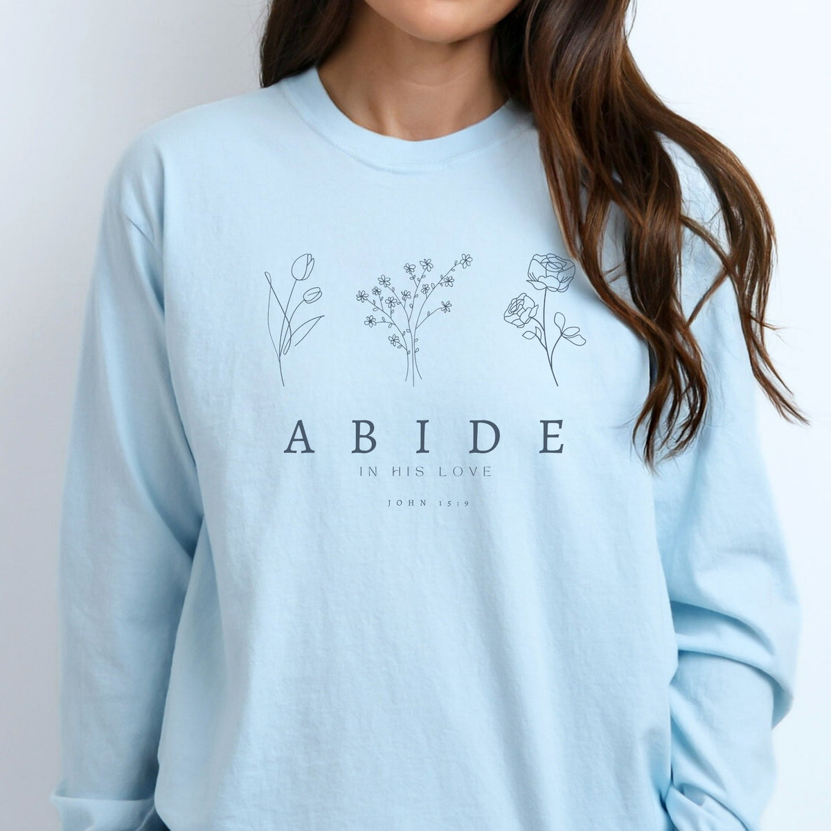 Light blue long sleeve tee with floral designs and text on a plain background