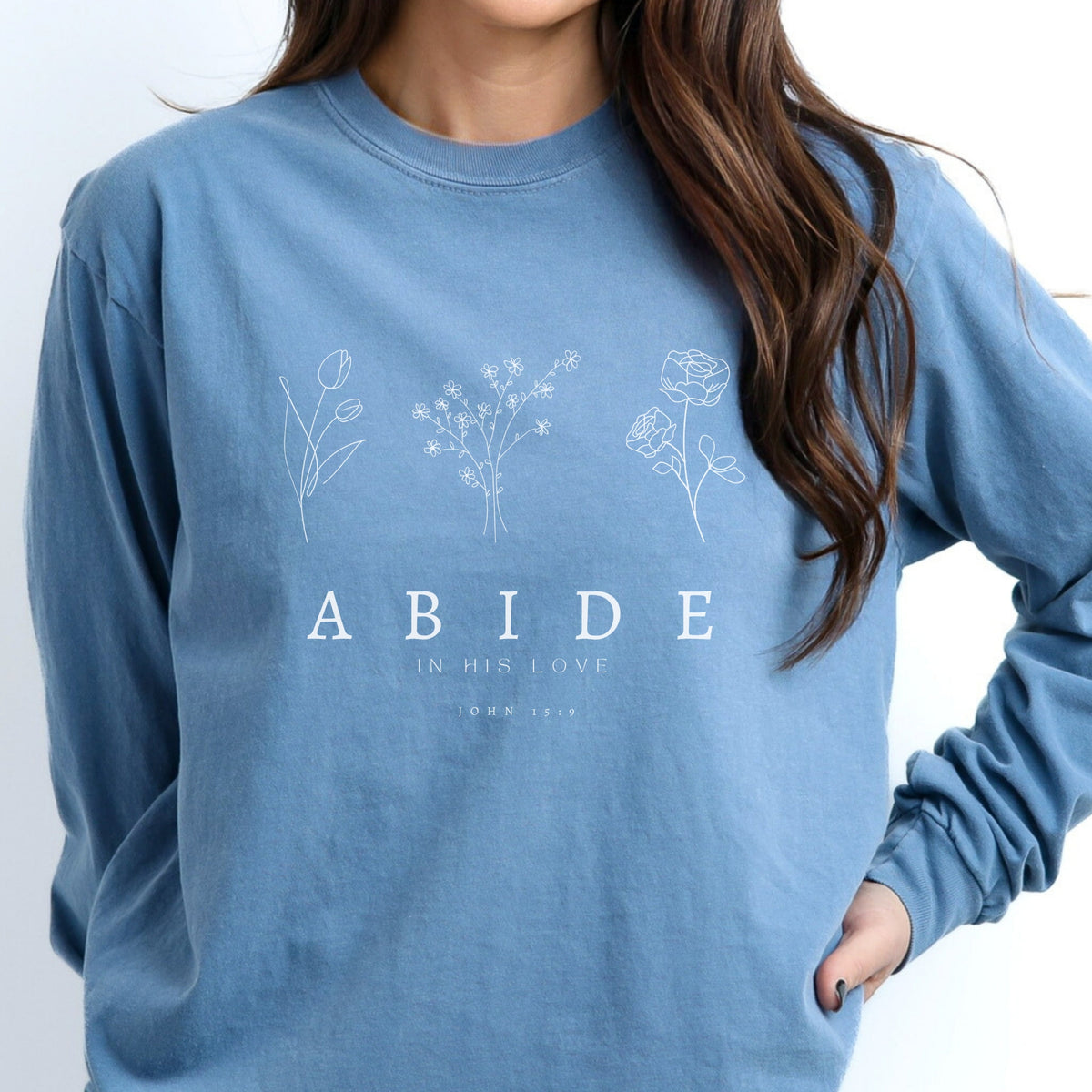 Person wearing a blue long sleeve tee with floral designs and text on a white background