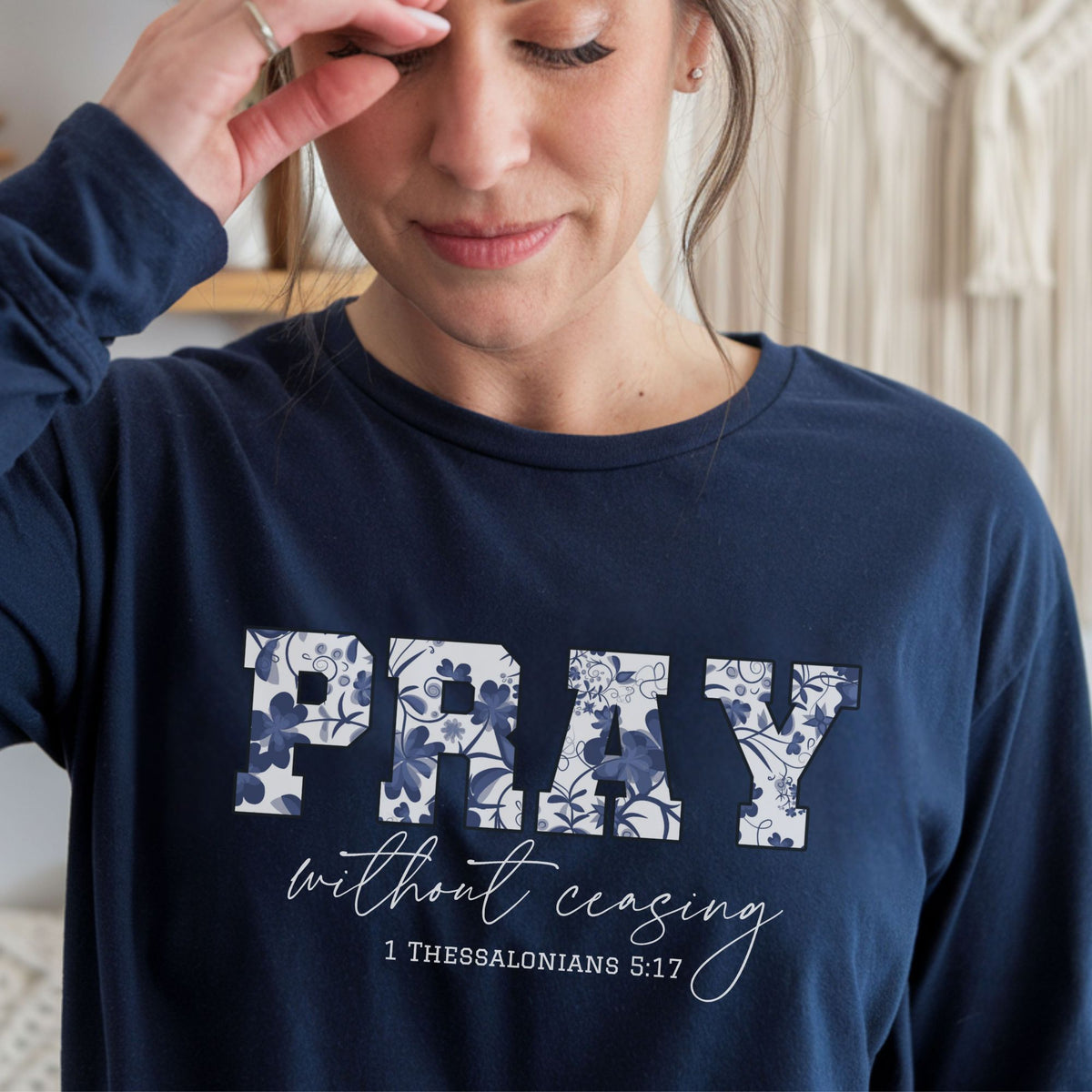 Person wearing a navy blue sweatshirt with 'PRAY without ceasing' text