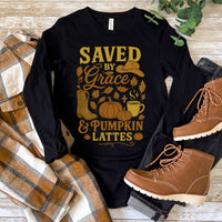 Black long-sleeve shirt with autumn-themed design and brown boots on a wooden surface.