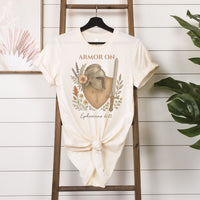 White t-shirt with 'Armor On' design on a wooden ladder against a white wall.