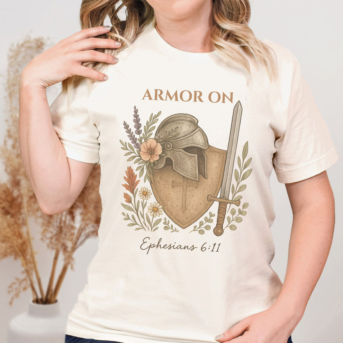 Person wearing a t-shirt with armor design and text, standing against a neutral background.