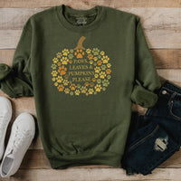 Green sweatshirt with pumpkin design and text on a wooden surface with shoes and jeans.
