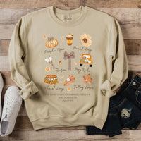 Beige sweatshirt with autumn-themed graphics and text on a wooden surface.