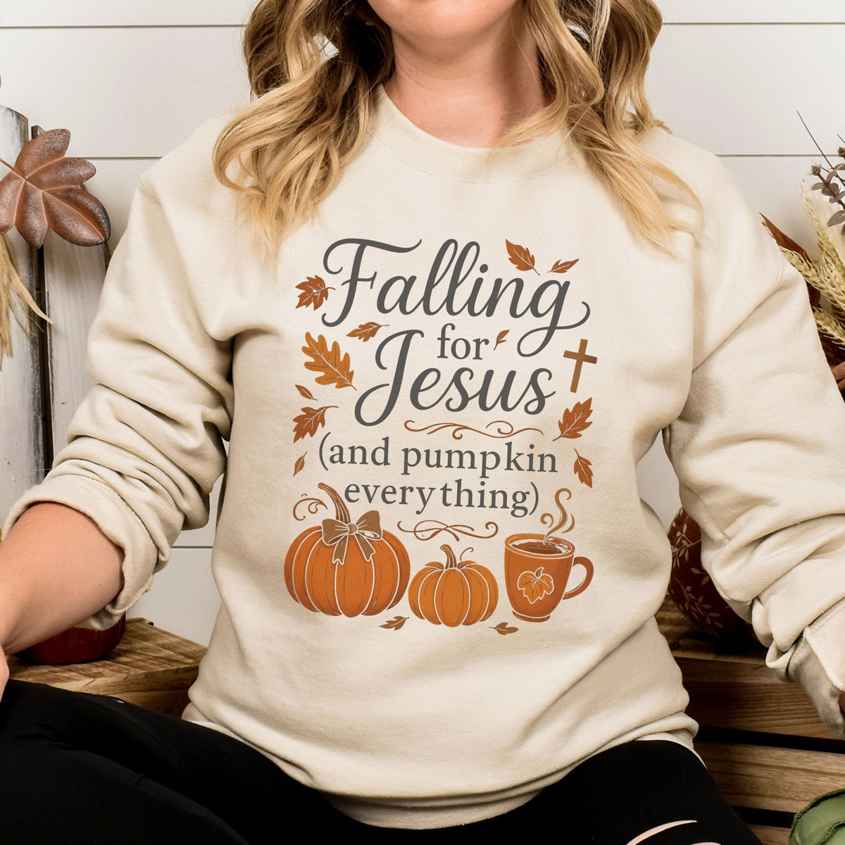Person wearing a cream-colored sweatshirt with 'Falling for Jesus (and pumpkin everything)' text and graphics.