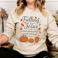 Person wearing a cream-colored sweatshirt with 'Falling for Jesus (and pumpkin everything)' text and graphics.