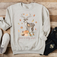 Gray sweatshirt with deer and pumpkin design on a wooden surface with shoes and jeans.