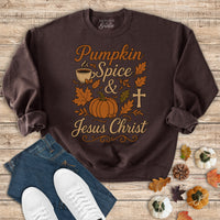 Brown sweatshirt with pumpkin spice and Jesus Christ design on a wooden surface with jeans and sneakers.