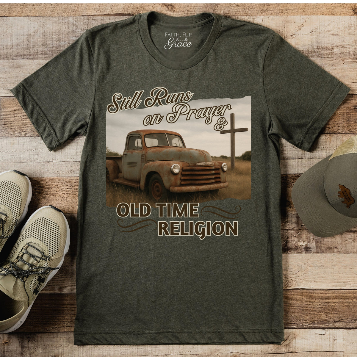 Green t-shirt with vintage truck graphic and text on a wooden surface with shoes and a hat.