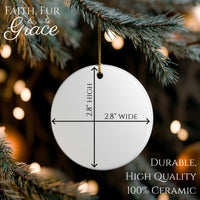 Circular ceramic ornament with dimensions hanging on a Christmas tree.