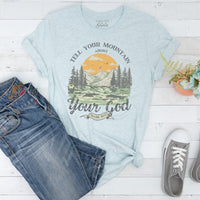 Light blue t-shirt with nature graphic and text, paired with jeans and sneakers on a white wooden surface.