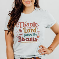 Person wearing a t-shirt with 'Thank the Lord and Pass the Biscuits' text on a plain background