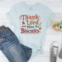 Light blue t-shirt with 'Thank the Lord and Pass the Biscuits' text on a wooden surface with jeans and sneakers.