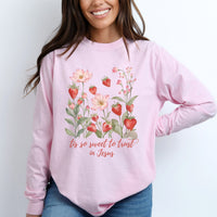 Person wearing a pink long sleeve tee with floral design and text