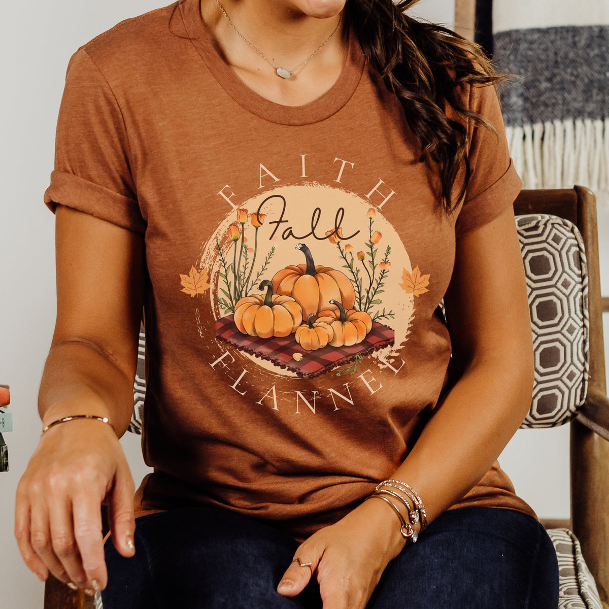 Person wearing an orange t-shirt with 'Faith, Fall, Flannel' design featuring pumpkins.