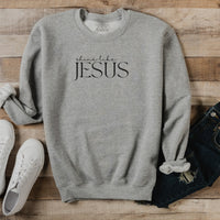 Gray sweatshirt with 'Shine Like Jesus' text on a wooden surface with shoes and jeans.