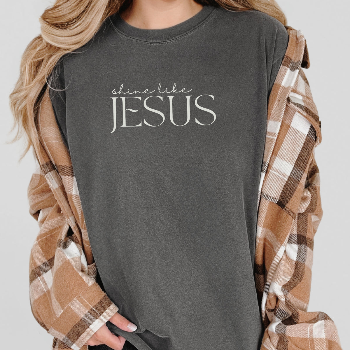 Person wearing a dark gray t-shirt with 'shine like JESUS' text, draped in a plaid shirt.