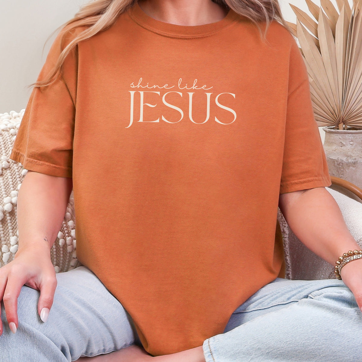 Person wearing an orange t-shirt with 'shine like Jesus' text.