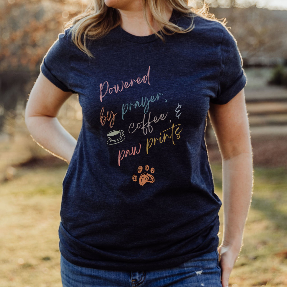 Person wearing a navy blue t-shirt with text and a paw print design outdoors.