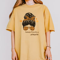 Yellow t-shirt with a graphic design and text worn by a person on a plain background