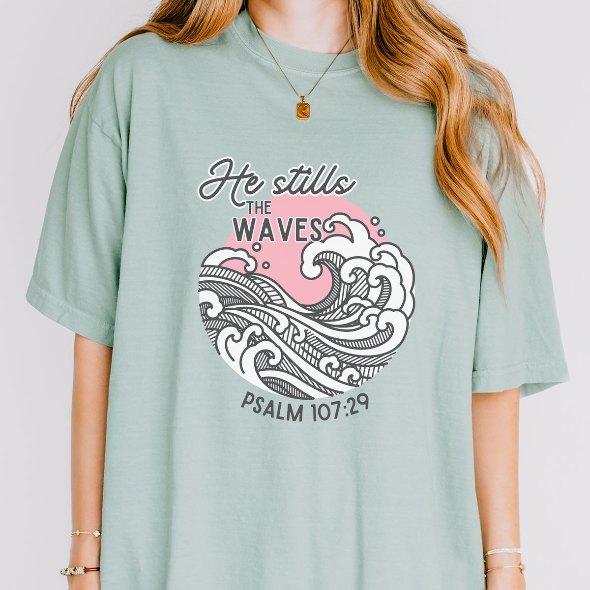 Person wearing a light green t-shirt with a wave design and text on a plain background