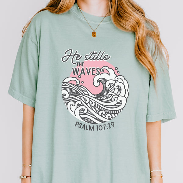 Person wearing a light green t-shirt with a wave design and text on a plain background