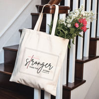 Tote bag with 'Stronger Than The Storm' text on a staircase