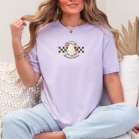 Woman wearing a light purple t-shirt with a ghost graphic and text, sitting on a couch.