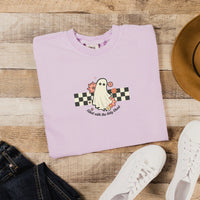 Folded light purple sweatshirt with a ghost design on a wooden surface