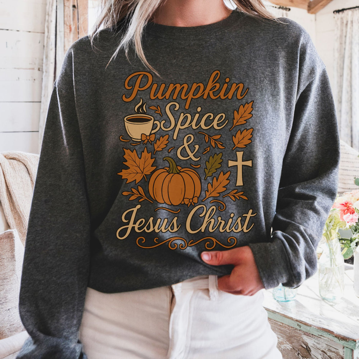 Person wearing a dark gray sweatshirt with 'Pumpkin Spice & Jesus Christ' text and graphics.