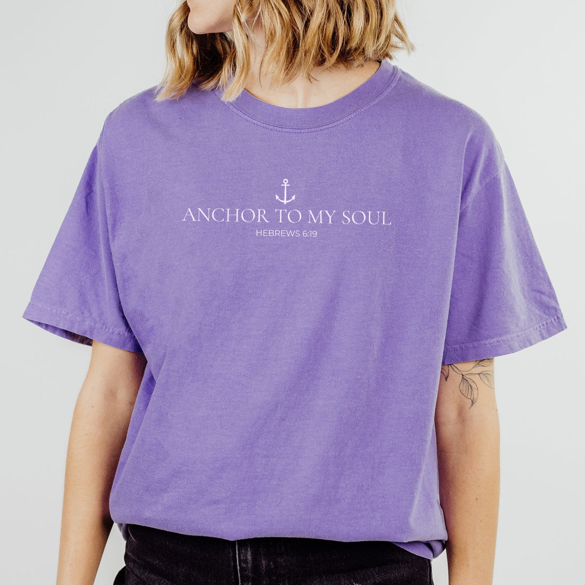 Person wearing a purple t-shirt with 'Anchor to My Soul' text on a plain background