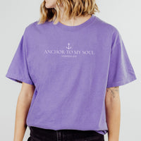 Person wearing a purple t-shirt with 'Anchor to My Soul' text on a plain background