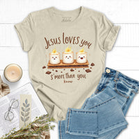 Beige t-shirt with 'Jesus loves you s'more than you know' design, paired with jeans and a candle on a white background.