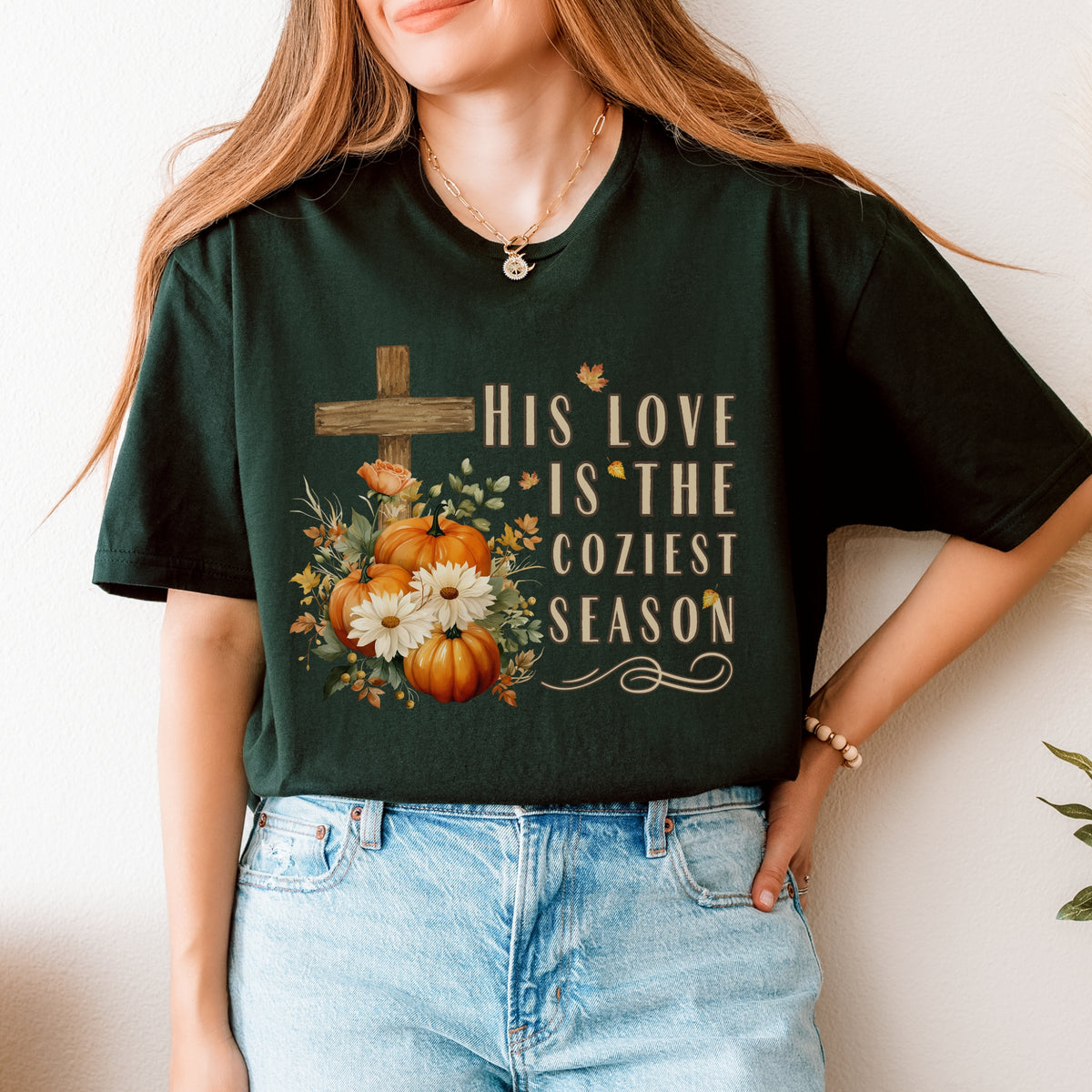 Person wearing a dark green t-shirt with a pumpkin and cross design and text.