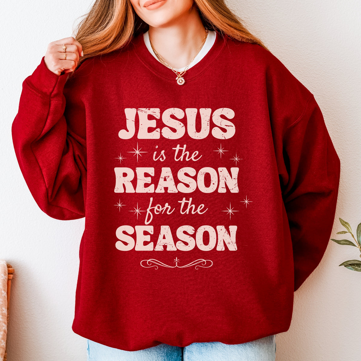 Red sweatshirt with 'Jesus is the Reason for the Season' text worn by a person.