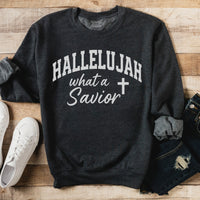 Dark gray sweatshirt with 'HALLELUJAH what a Savior' text on a wooden surface with white sneakers and jeans.