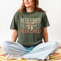 Person wearing a green t-shirt with 'REDEEMED' text and a bow graphic.