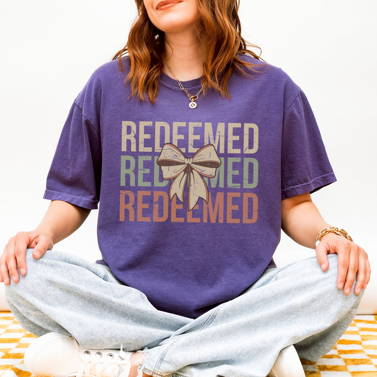 Person wearing a purple t-shirt with 'REDEEMED' text and a bow graphic.