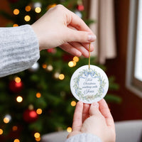 Person holding a Christmas ornament with a tree in the background