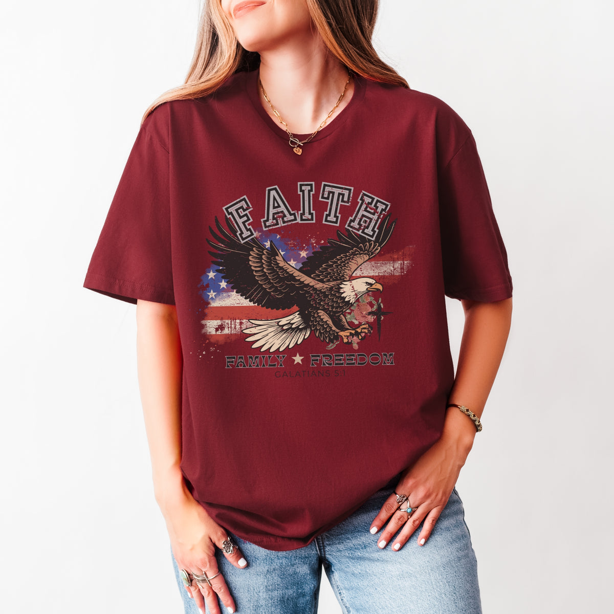 Person wearing a maroon t-shirt with an eagle graphic and text on a plain background