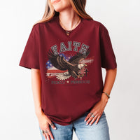 Person wearing a maroon t-shirt with an eagle graphic and text on a plain background