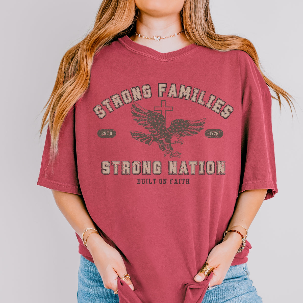 Person wearing a red t-shirt with 'Strong Families Strong Nation Built on Faith' text and eagle graphic.