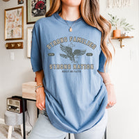 Person wearing a blue t-shirt with text and an eagle graphic in a room.