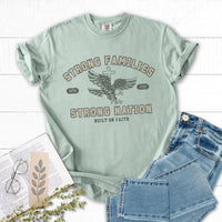 Mint green t-shirt with graphic design and text, paired with jeans and a book on a white surface.