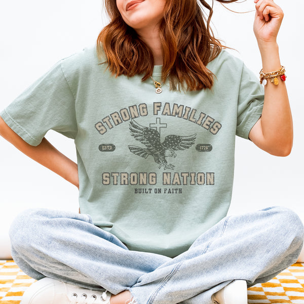 Person wearing a light green t-shirt with 'Strong Families Strong Nation' text and graphic.
