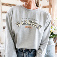 Person wearing a gray sweatshirt with 'Raising Warriors for Christ' text in a casual setting.